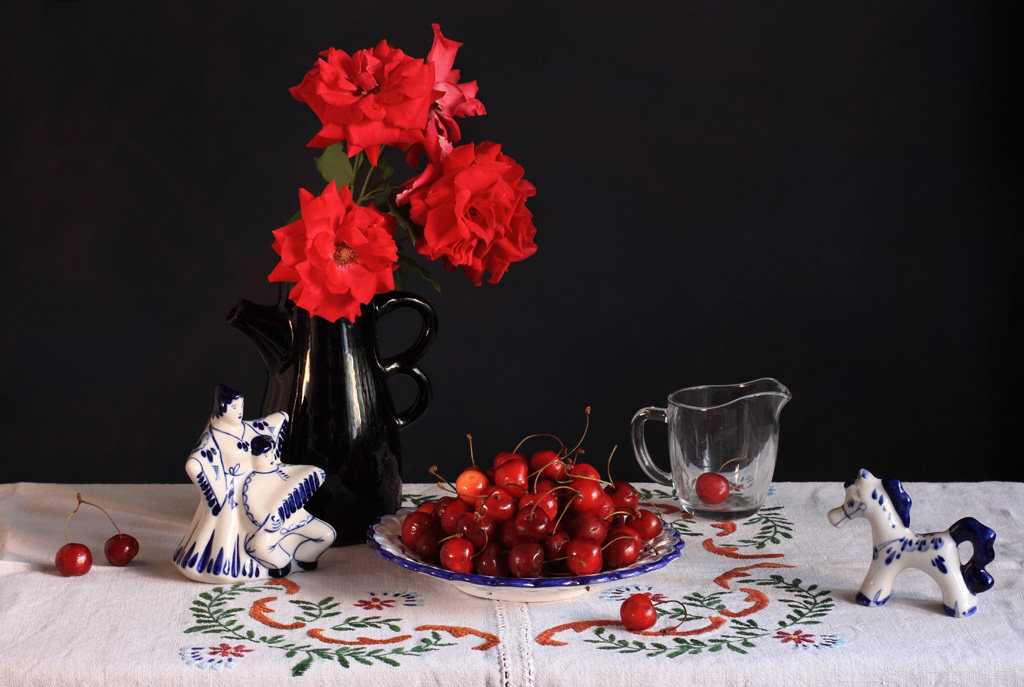 Фото Красные розы в вазе, тарелка с черешней, стеклянный стакан с ягодой черешни и статуэтки гжель, фотограф Наталья Панга