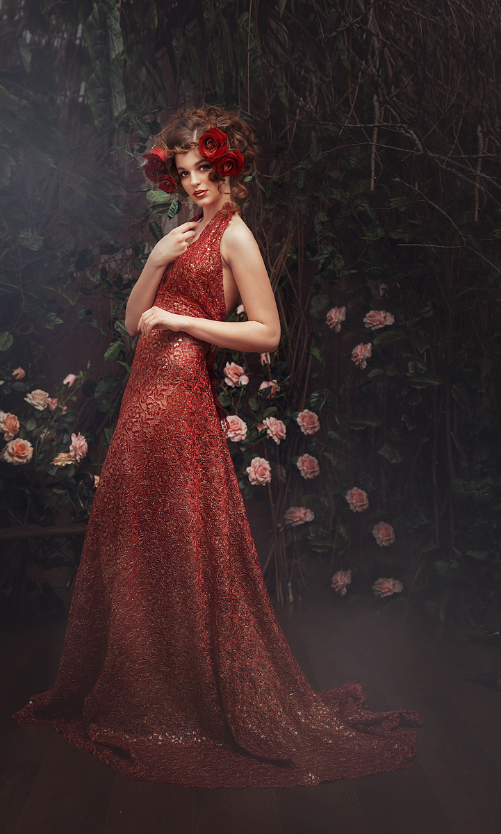 Фото Девушка в вечернем платье с розами в волосах стоит на фоне розовых