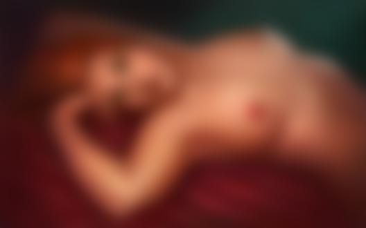 Фото Обнаженная рыжеволосая девушка с красивой грудью лежит на красной ткани
