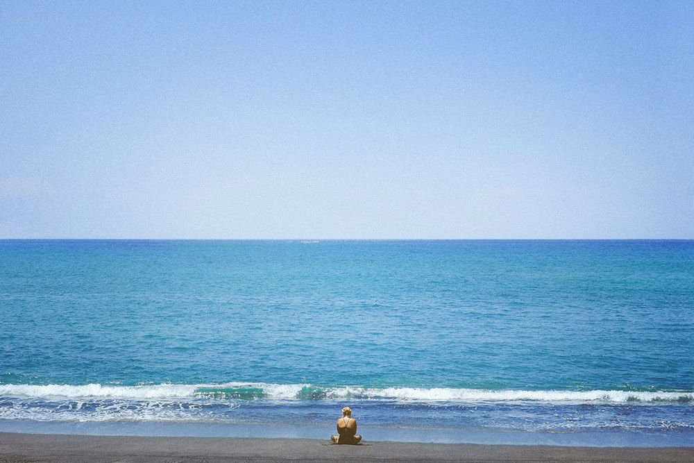 Фото Девушка сидит в позе лотоса на берегу моря
