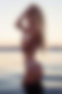 Фото Красивая девушка блондинка стоит в воде прикасаясь пальцем к губам