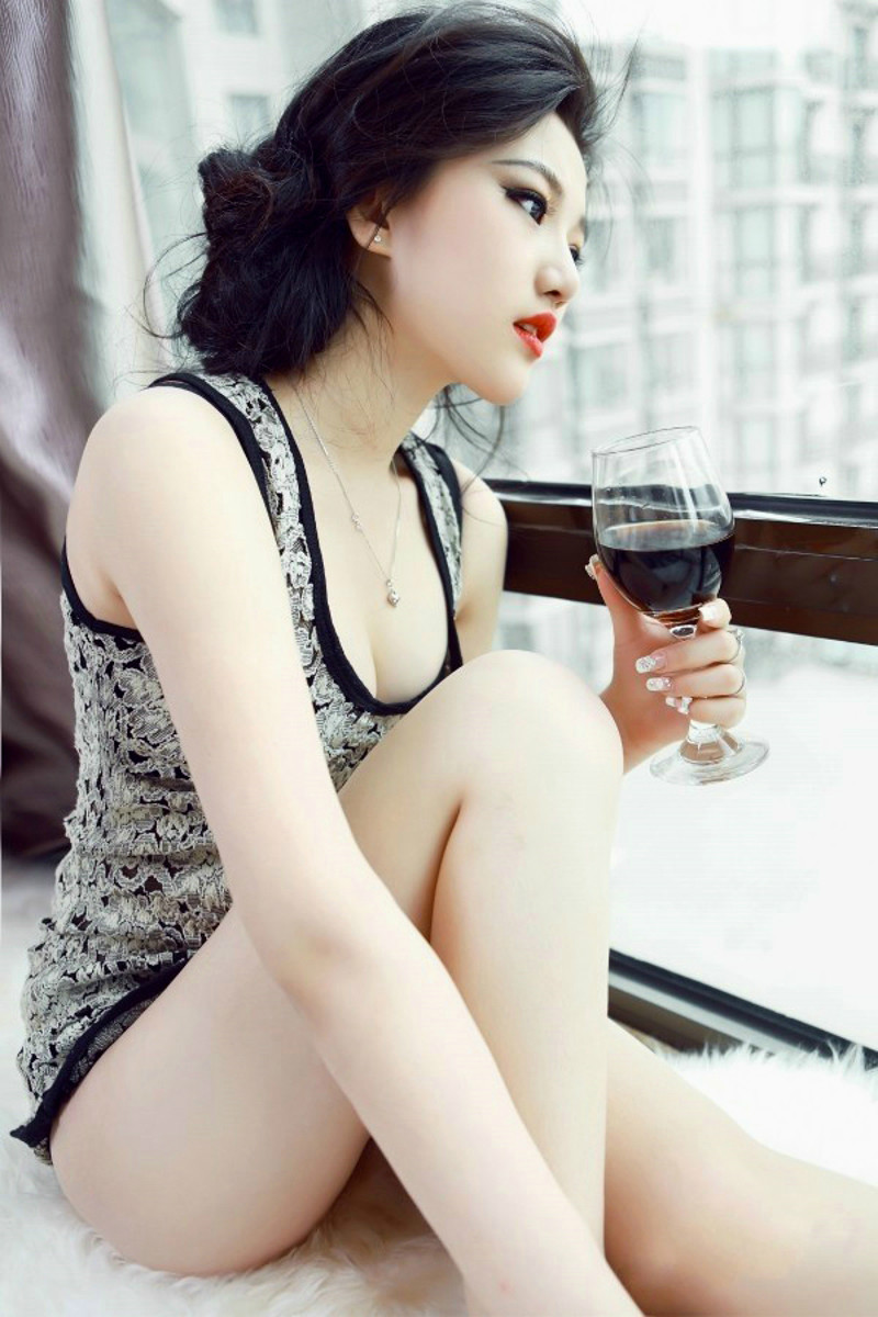Фото Красивая девушка держит в руке бокал с напитком смотря в окно