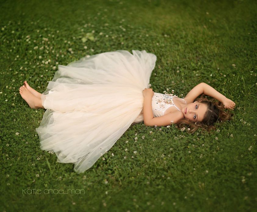 Фото Красивая девочка в пышном белом длинном платье лежит на лугу, by Katie Andelman