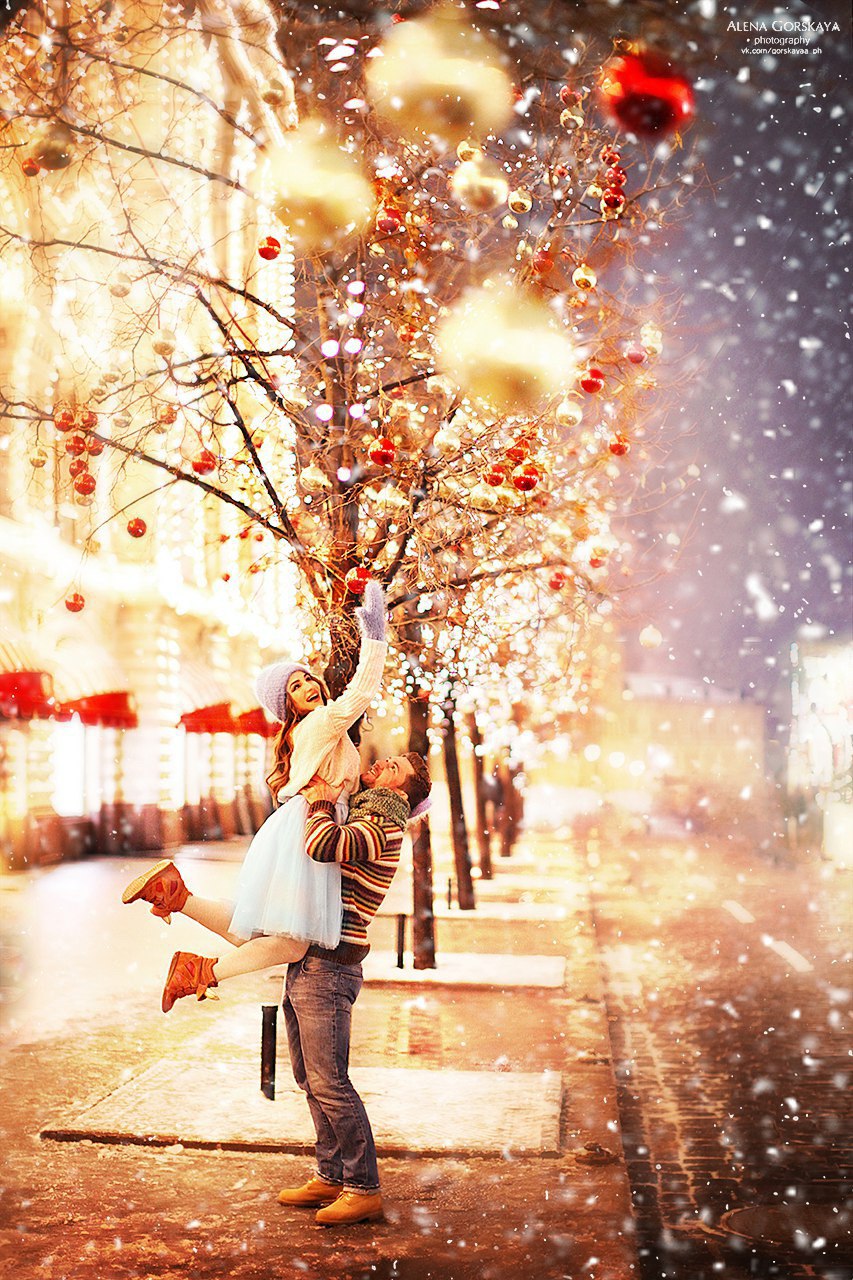 Фото Мужчина держит девушку на руках, которая хочет снять с дерева новогоднюю игрушку, фотограф Алена Горская