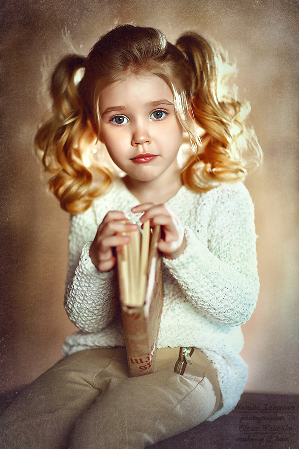 Фото Очень милая красивая девочка голубоглазая с хвостиками, держит в руках книгу, фотограф Наталья Законова