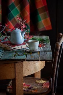 Фото Стул у стола, где стоит чайник на книге и чашка на блюдце