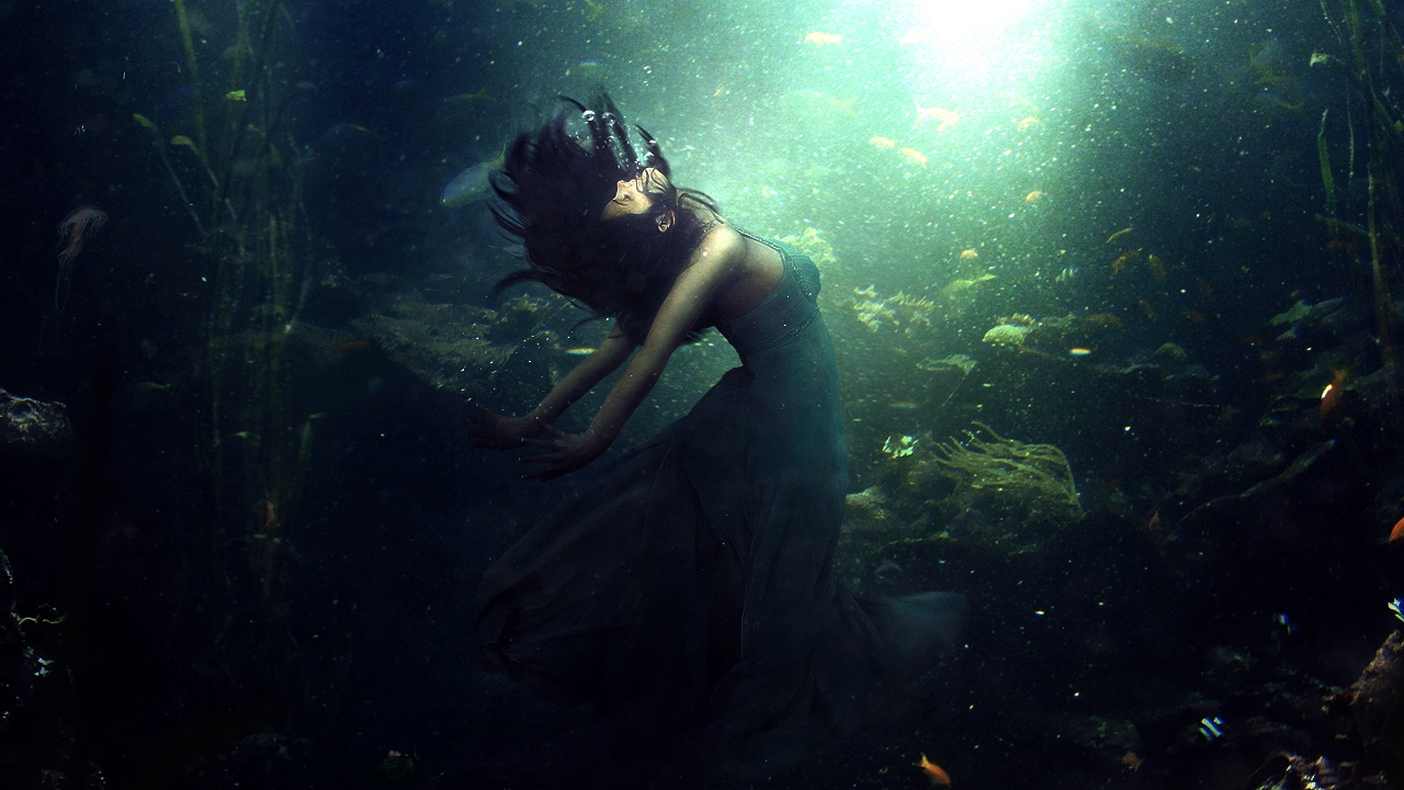 Фото Девушка под подой в окружении рыб и растений тянется к свету на поверхности