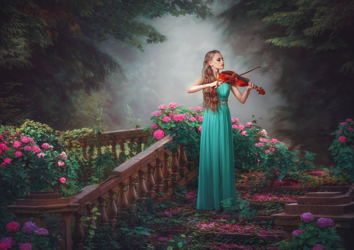 Фото Девушка в длинном зеленом платье, стоит на ступенях лестницы, усыпанной лепестками цветов и играет на скрипке, на фоне природы и цветущих кустов. Фотохудожник Наталья Макушева