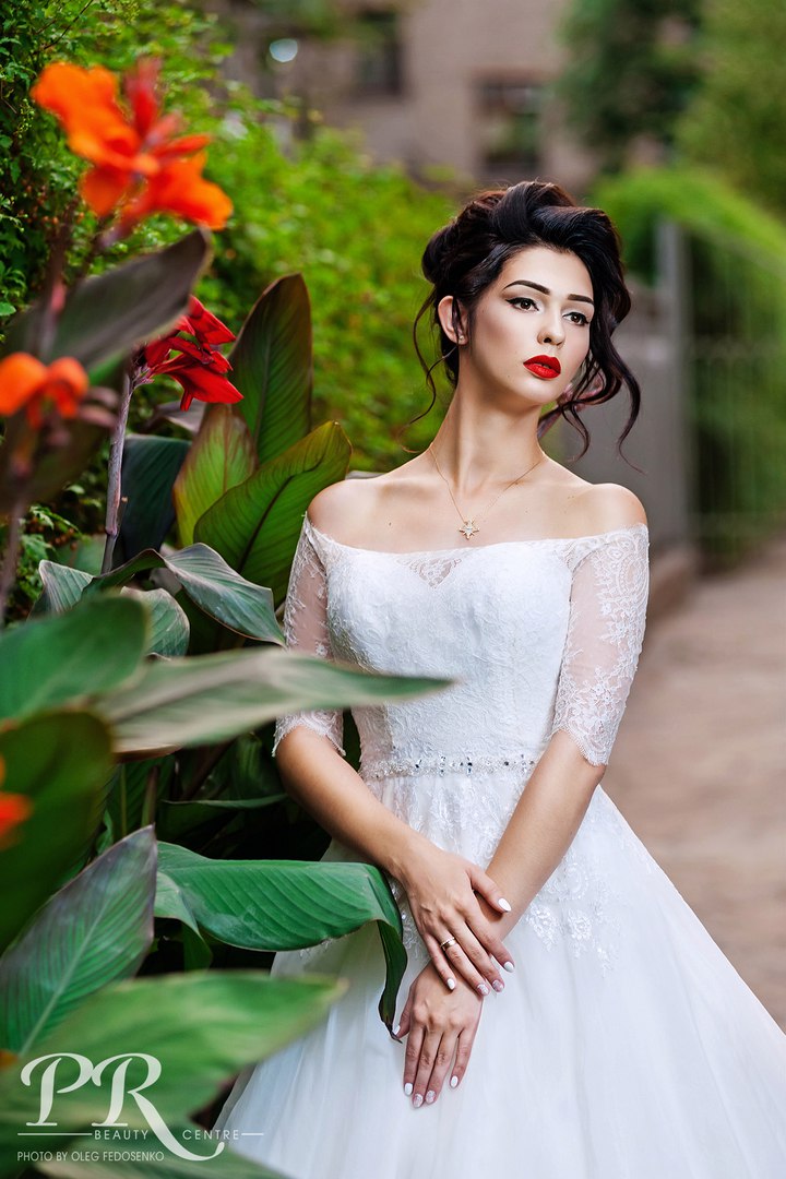 Фото Модель Юлия с каштановыми волосами, в белом платье стоит у веток с цветами на размытом фоне природы. Фотограф Олег Федосенко