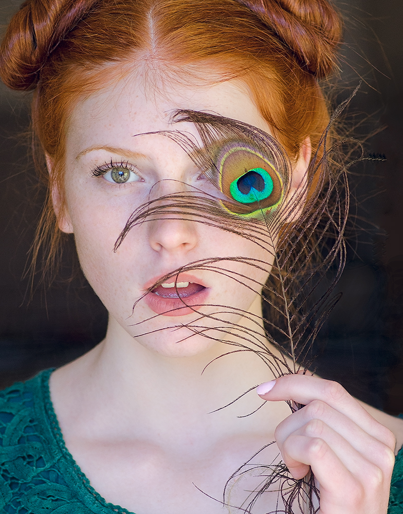 Фото Портрет рыжеволосой девушки с открытым ртом и пером павлина у лица. Фотограф Таня Маркова