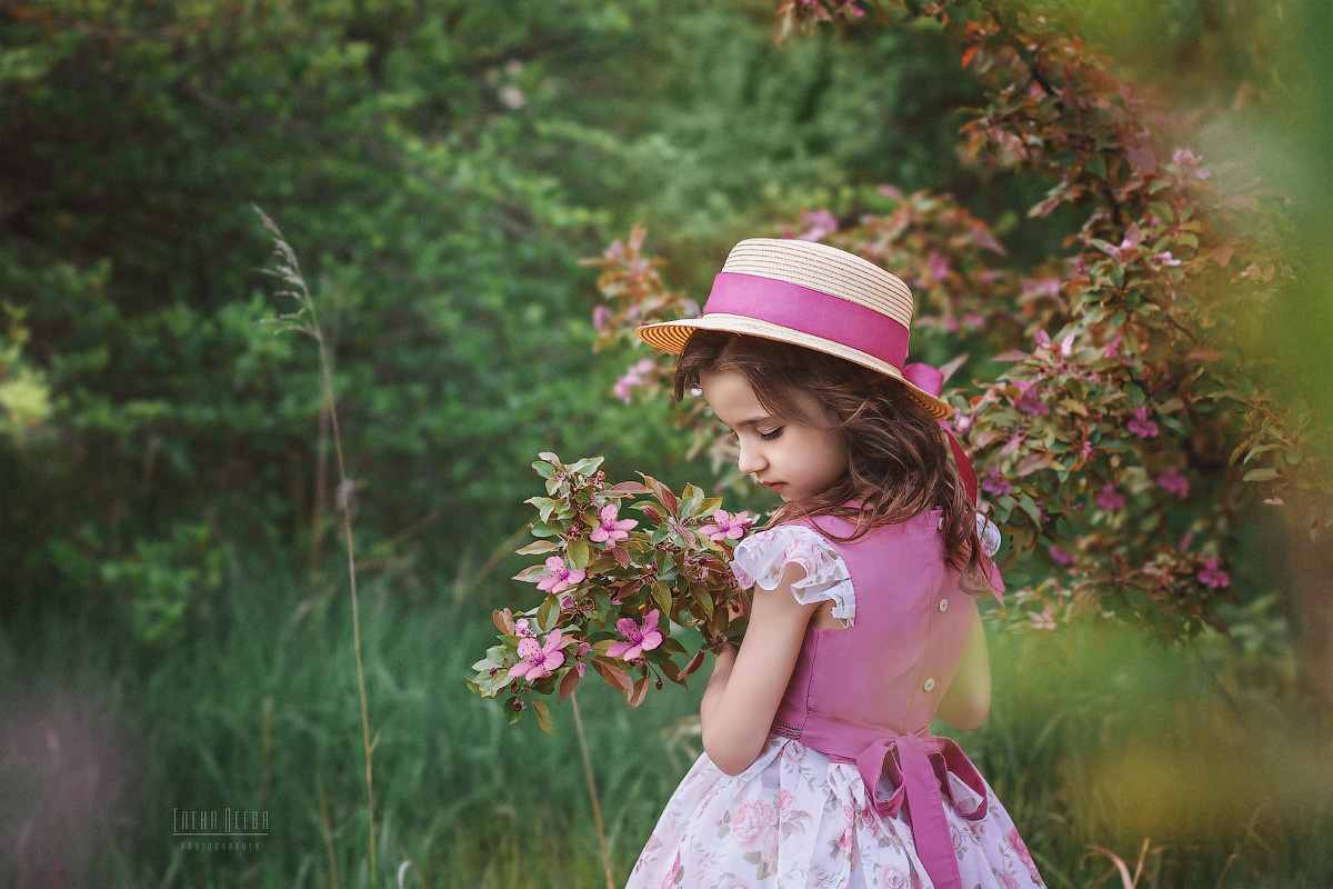 Фото Девочка в шляпке стоит у цветущей ветки дерева. Фотограф Деева Елена
