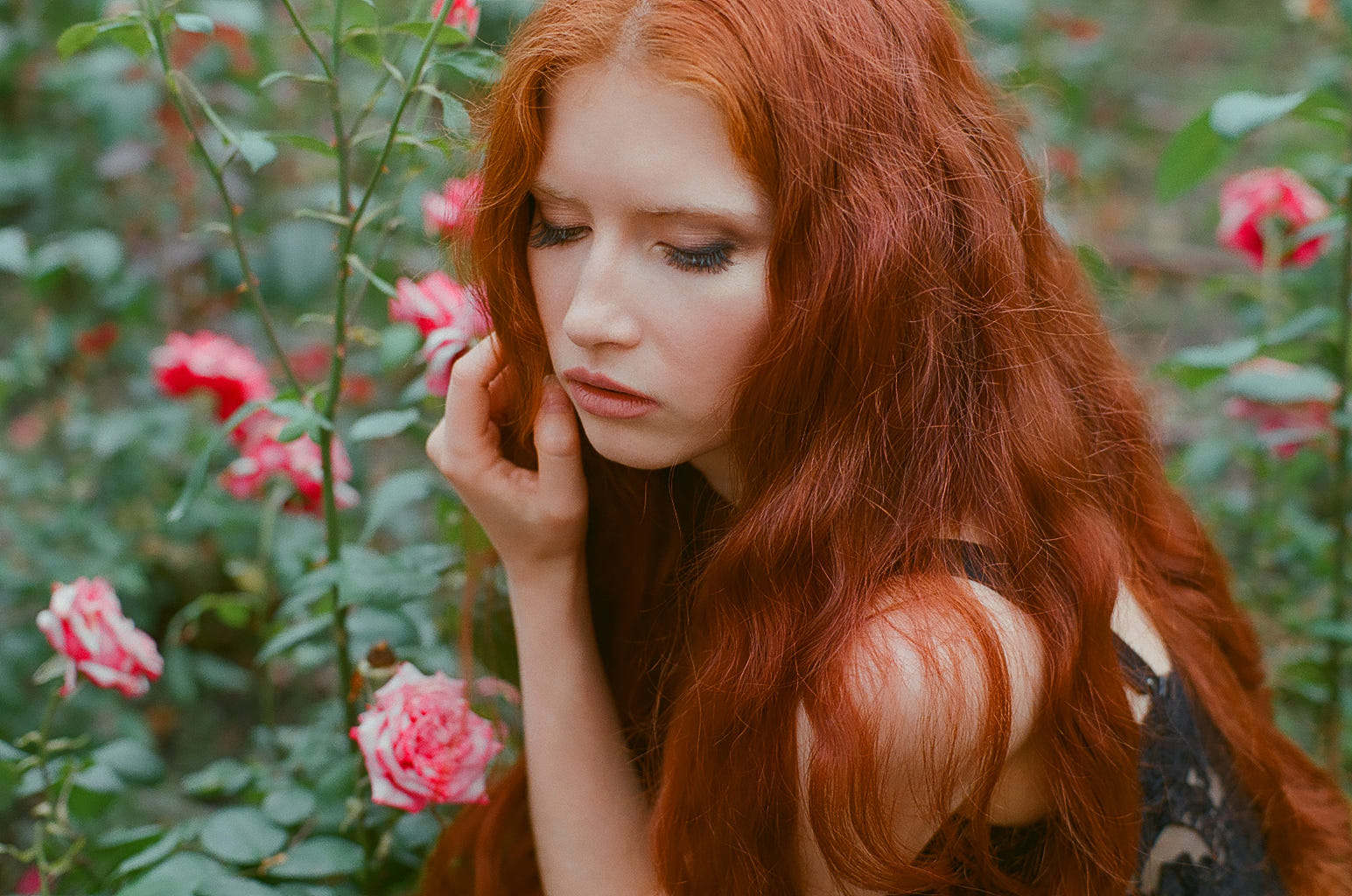 Фото Рыжеволосая девушка с опущенными глазами сидит перед кустами роз, фотограф Ekaterina Skobel