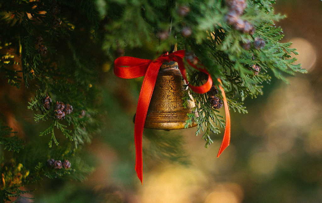 Фото Колокольчик с красным бантиком висит на хвойном дереве