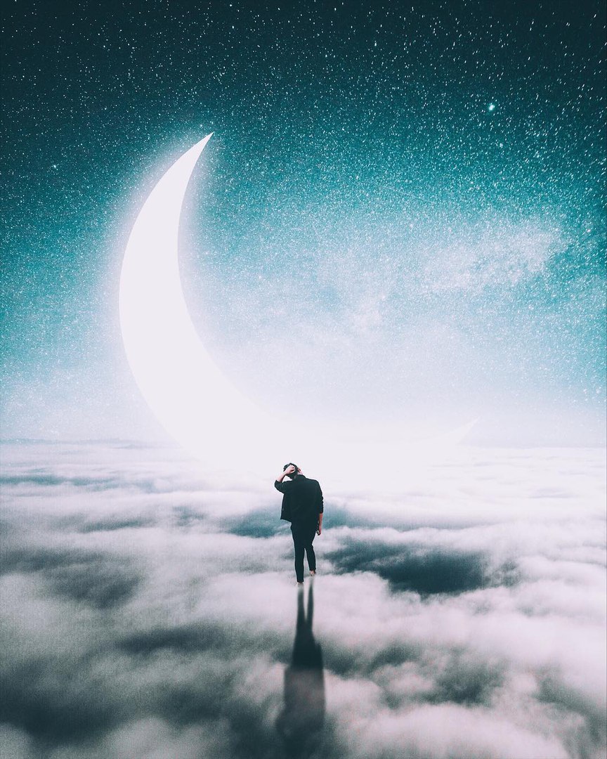 Фото Парень стоит в облаках, над которыми возвышается полумесяц, в ночном небе