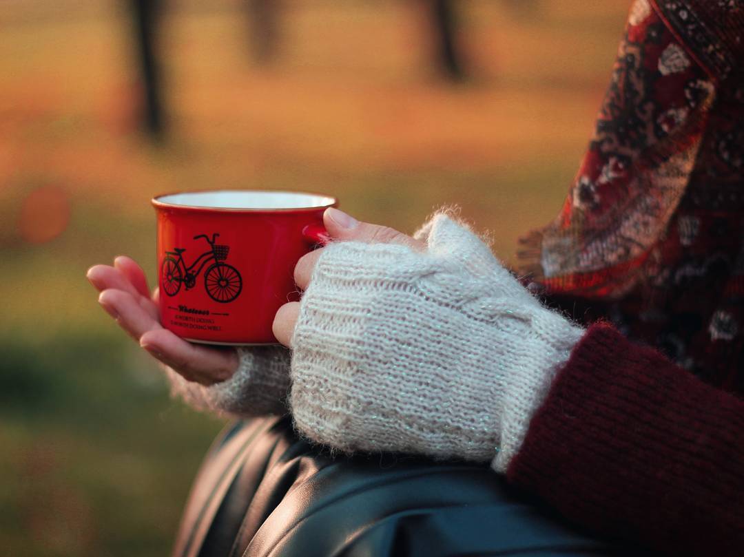 Фото В руке девушки чашка, с нарисованным на ней велосипедом