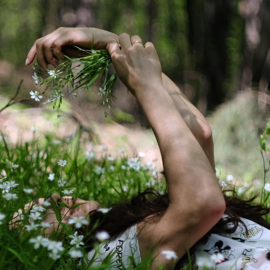 Фото Девушка с весенними цветами в руке лежит в зеленой траве, by madzik5555