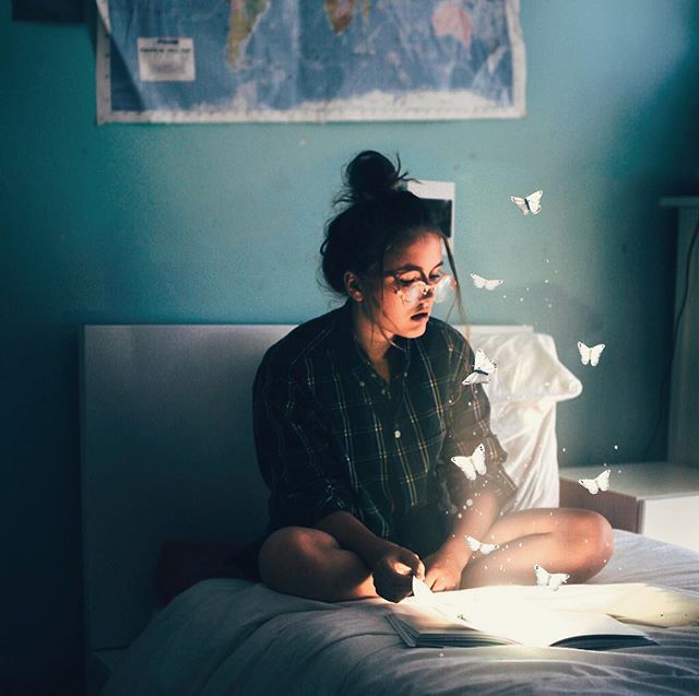 Фото Девушка в очках, сидя на кровати, читает книгу со светящимися страницами, над которыми порхают белые бабочки, by fetching_tigerss (Annegien)