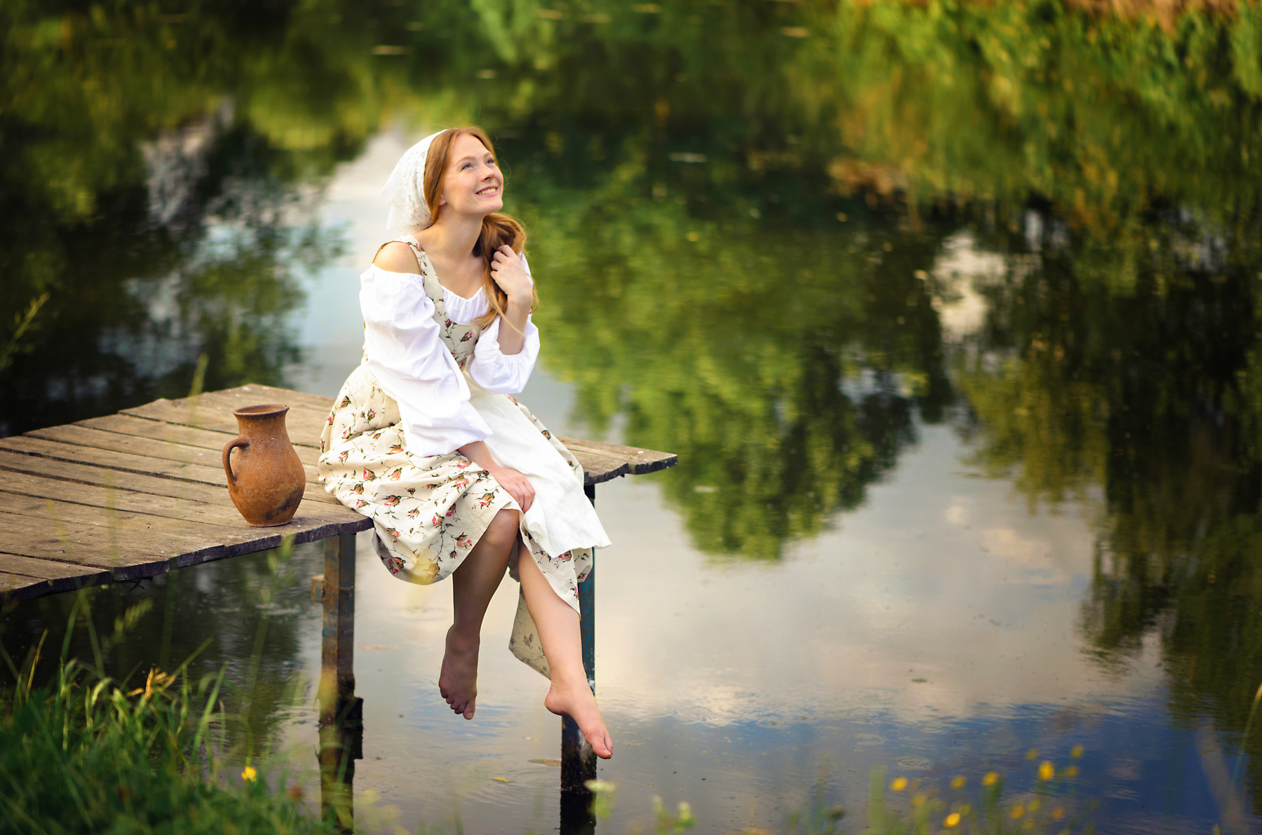 Фото Девушка сидит на мостике у озера, в воде которого отражаются ...