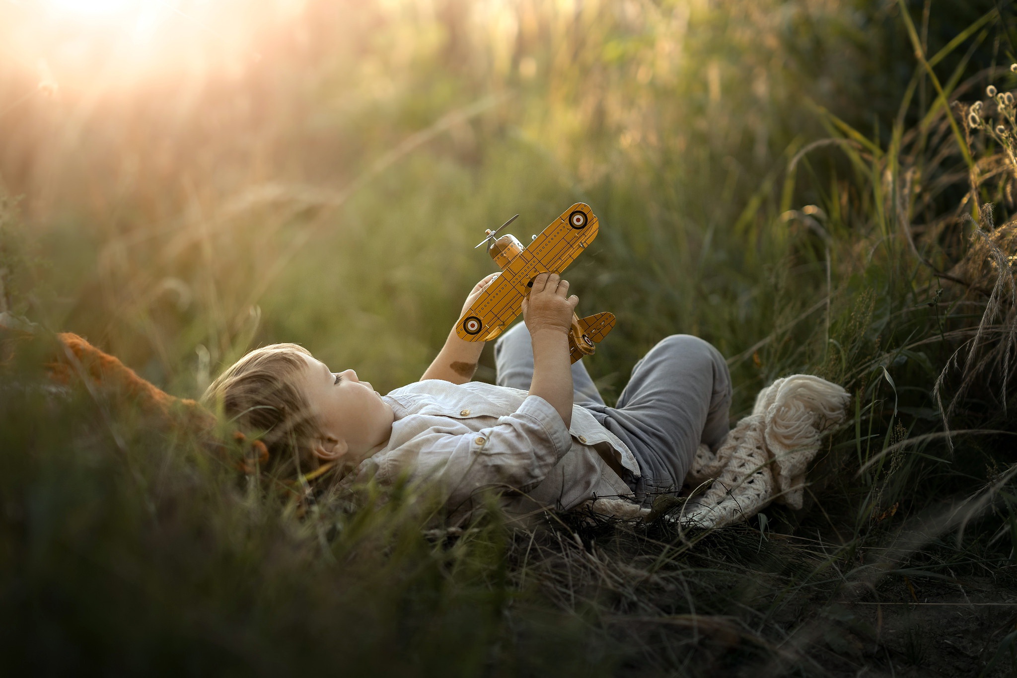Фото Мальчик с игрушечным самолетиком лежит в траве, фотограф Iwona Podlasinska