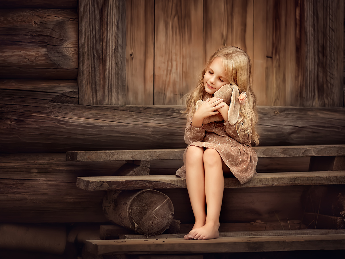 Фото Милая девочка с игрушечным зайчиком сидит на ступеньках. Фотограф Елена Михайлова