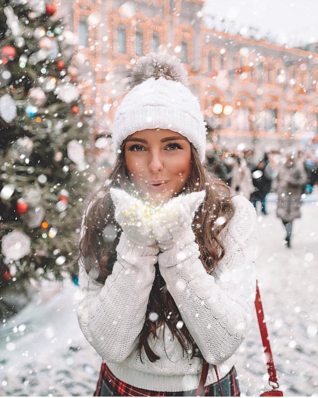 Фото Девушка сдувает снег с рук в варежках