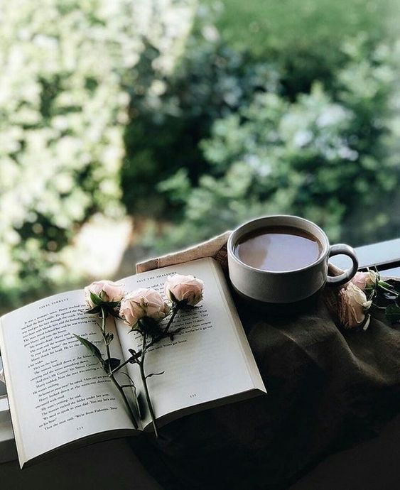 Фото Цветы на открытой книге и чашка кофе у открытого окна