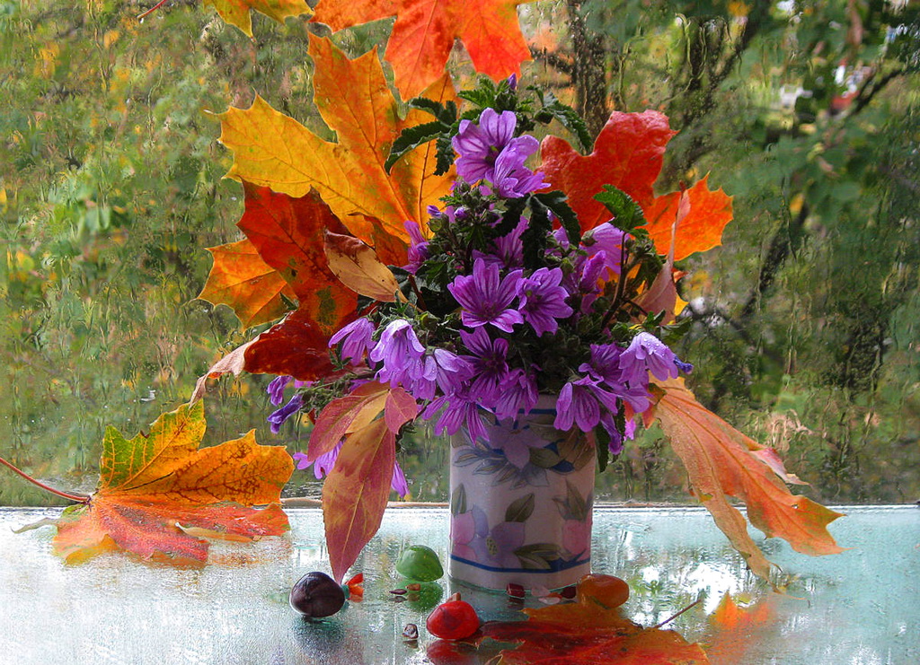 Фото Букет из осенних листьев и цветов в фарфоровой вазе на столе переддождливым окном