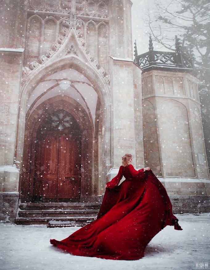 Фото Девушка в красном платье стоит у здания под падающим снегом. Фотограф Светлана Беляева
