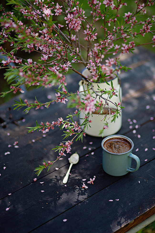 Фото Кружка кофе на столе и бидончик с весенней веткой на столе