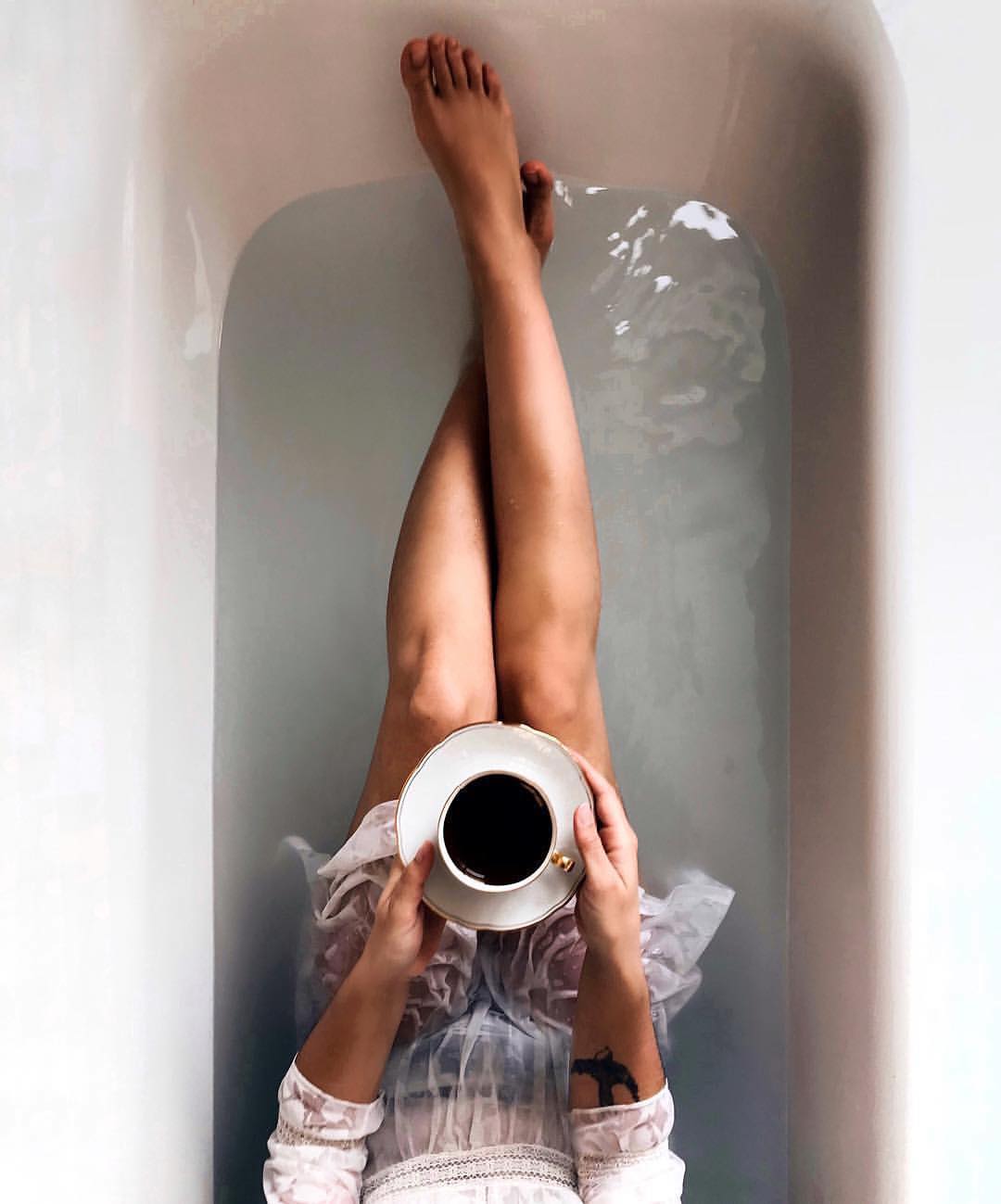 Фото Девушка с чашкой кофе на блюдце сидит в ванне