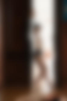 Фото Модель Kate Klein в расстегнутой белой блузе и бусами на шее стоит у двери. Фотограф - Дмитрий Бугаенко