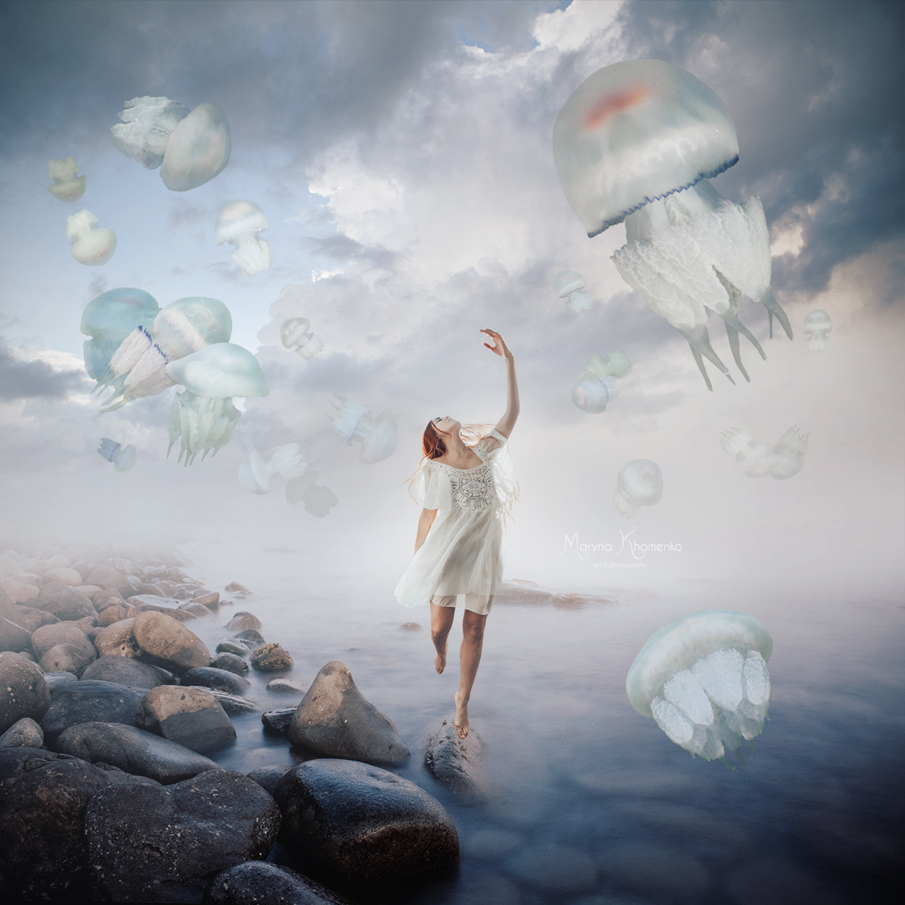 Фото Девушка стоит над водой, приподняв руку к парящим в небе медузам, by Maryna Khomenko