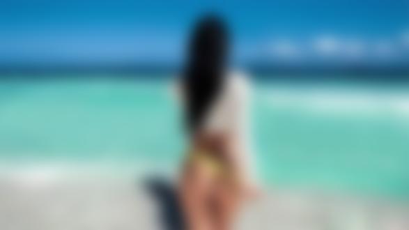 Фото Девушка с длинными волосами стоит к нам спиной на фоне моря