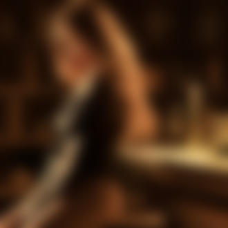 Фото Девушка с длинными волосами сидит у стола с бутылкой и бокалом шампанского