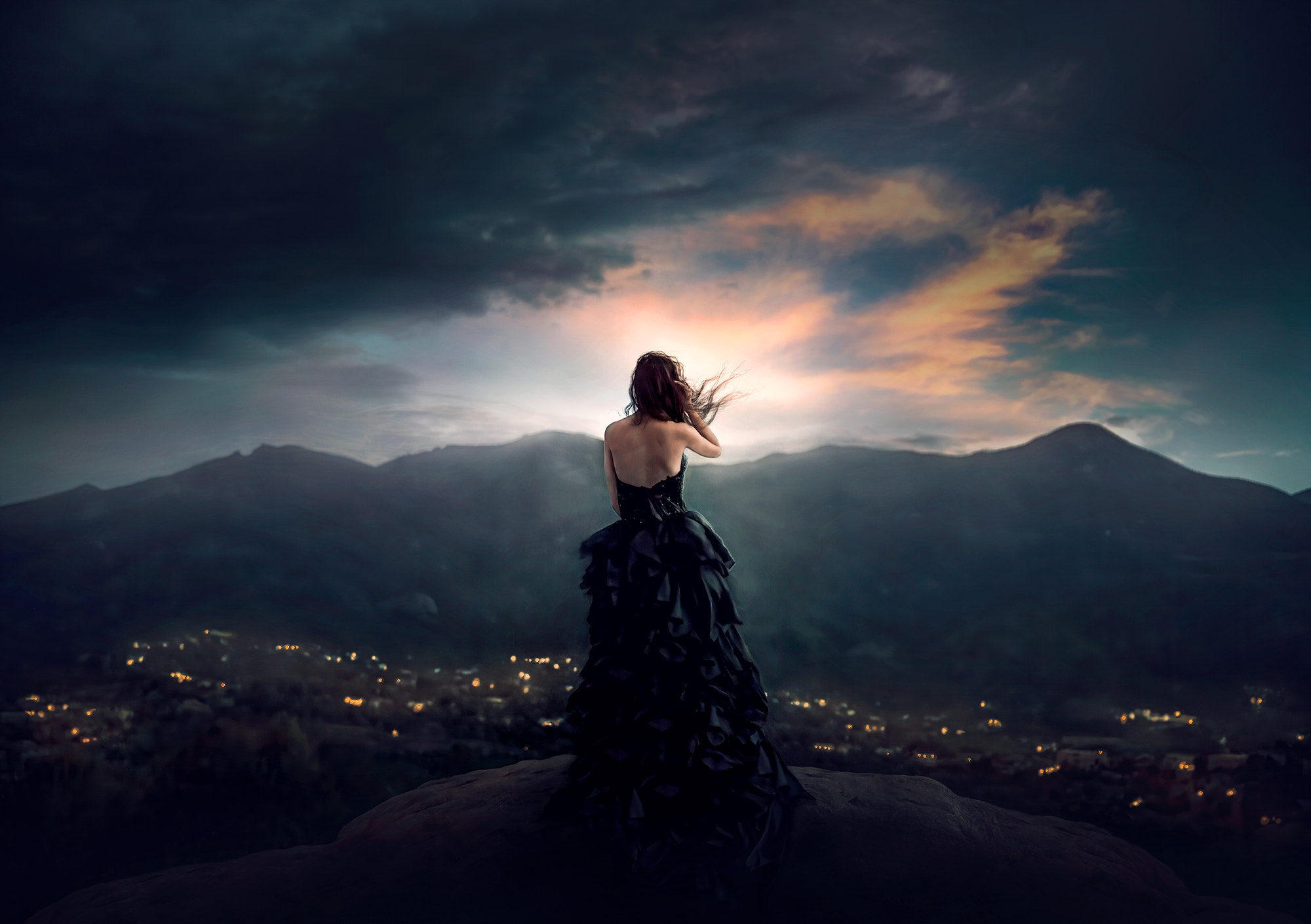 Фото Девушка в длинном платье стоит на фоне ночного города, гор под облачным небом, by Jessica Drossin