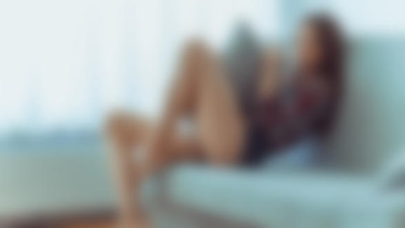 Фото Девушка в шортах м клетчатой рубашке сидит на диване