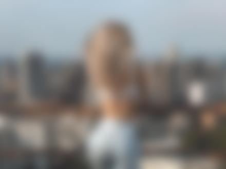 Фото Девушка - блондинка стоит на фоне города спиной к нам