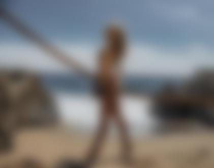 Фото Обнаженная модель Emilee Ann Miller со шляпой в руке стоит на песке у каната. Фотограф Kesler Tran