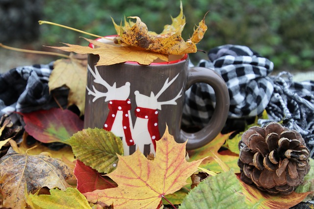 Фото Возле лежащего человека стоит чашка с чаем, с нарисованными оленями, прикрытая осенними листьями
