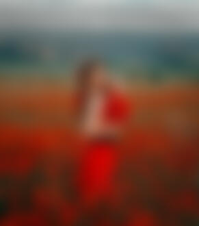 Фото Девушка Алина в красной юбке стоит на цветущем поле с букетом маков в руке