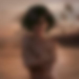 Фото Девушка, прикрыв руками грудь, стоит на фоне морского побережья с пальмами на ветру