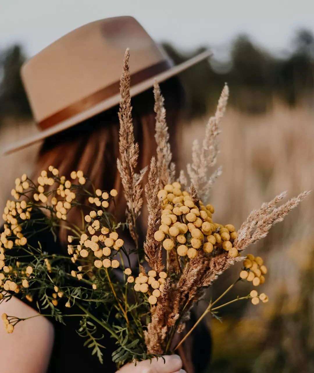 Фото Девушка в шляпе с полевыми цветами в руке