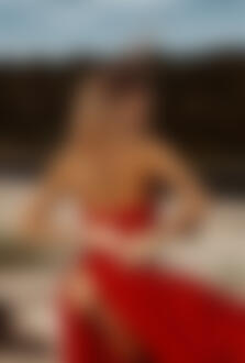 Фото Девушка - блондинка с короной в красном платье с оголенной попкой держит руки за спиной