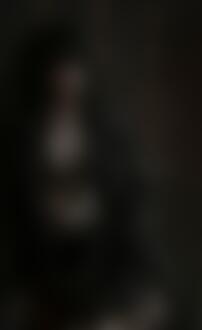 Фото Темноволосая девушка в распахнутом жакете стоит у стены