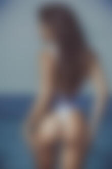 Фото Модель Мари с длинными волосами, держа руки у попки, стоит на фоне моря