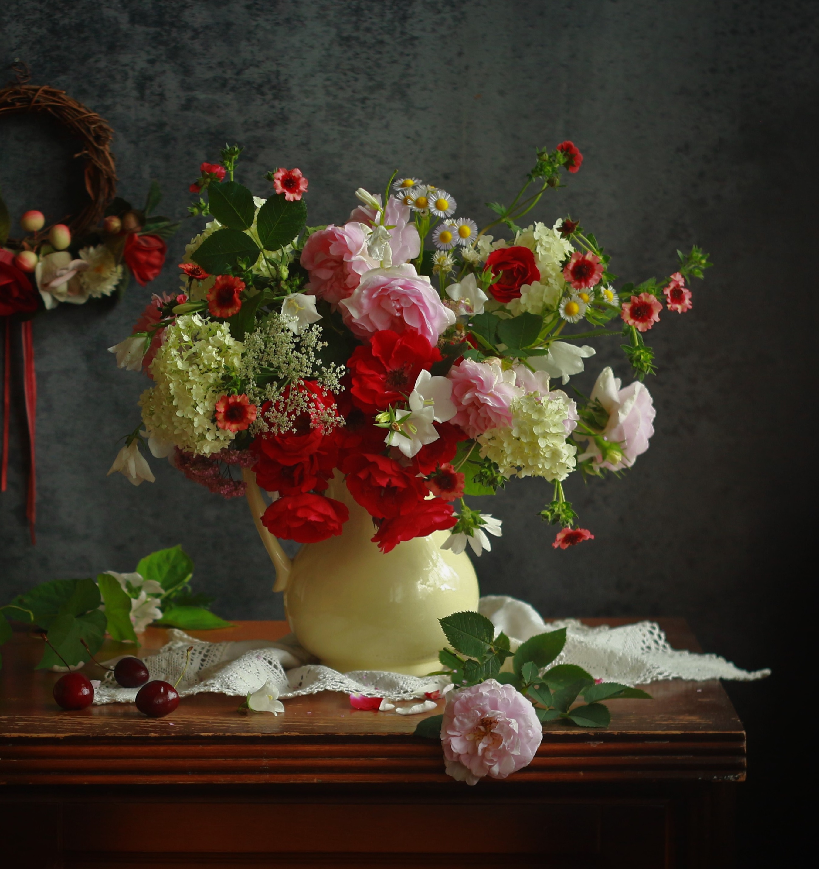 Фото Букет из роз, ромашек, петуний и гортензии в кувшине на тумбочке