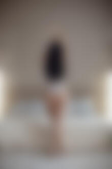 Фото Модель Настя в нижнем белье, с поднятыми вверх руками стоит перед кроватью