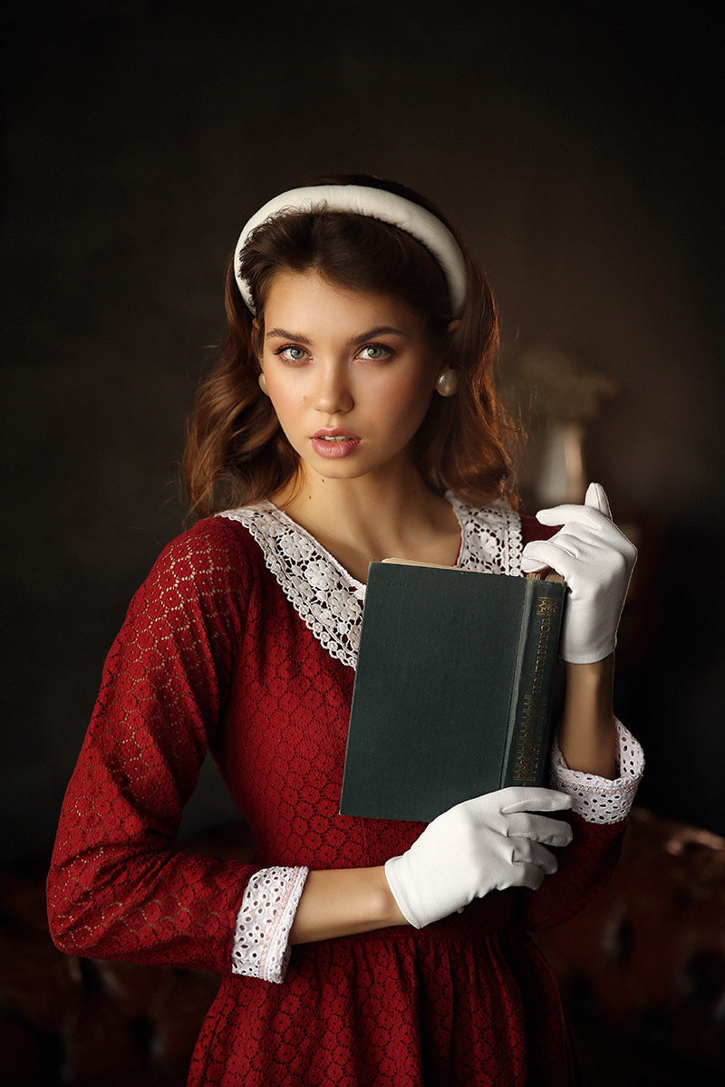 Фото Модель Ксения в красном платье, в белых перчатках держит в руках книгу