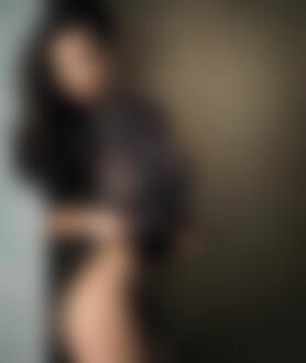 Фото Модель-брюнетка Ника стоит у стены в серой футболке и черном белье