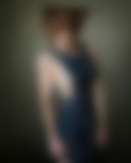 Фото Модель Анна Кудинова позирует в темно-синем платье в цветочек на фоне стены